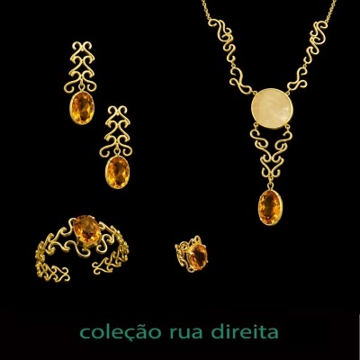 Conjunto de joias douradas com pedras âmbar sobre fundo preto