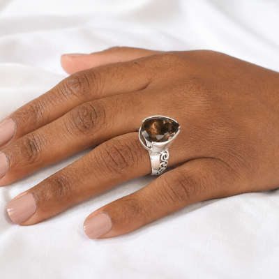 Anel de prata com pedra castanha em mão feminina com unhas pintadas