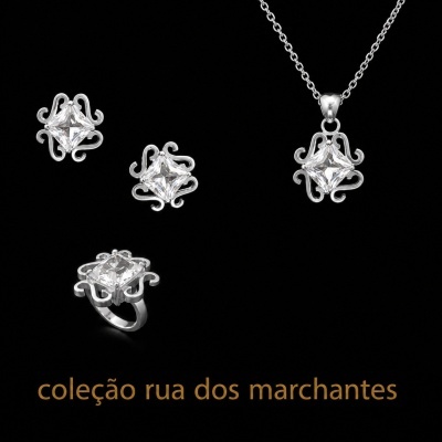 Conjunto de joias prata com pedras quadradas transparentes sobre fundo preto.
