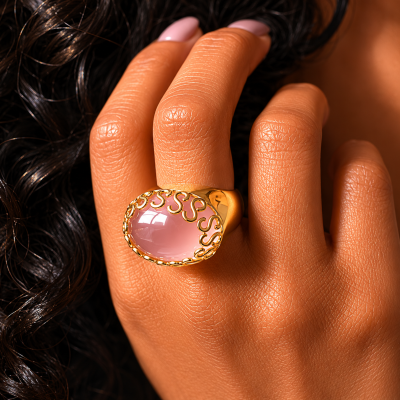 Anel dourado com pedra rosa oval num dedo bronzeado