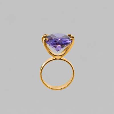 Anel dourado com pedra violeta em fundo cinza