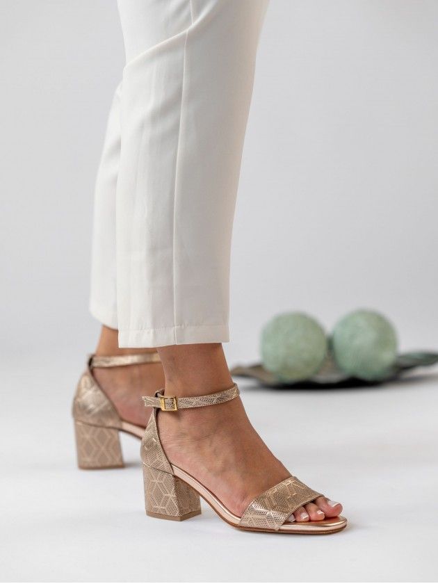 Sandálias MLV Claudia.31 Rose Gold Sandálias douradas de salto bloco com padrão geométrico usadas com calças brancas.