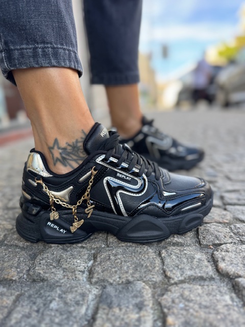 Sapatilhas Replay Destiny W Clean Black Ténis pretos com detalhes metálicos e correntes douradas pendentes na calçada
