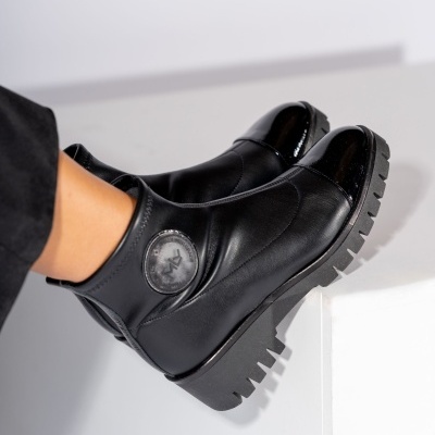 Botins pretos de couro com sola antiderrapante e detalhe circular no tornozelo.