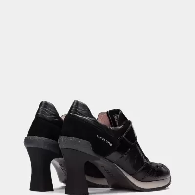Sapatos pretos de salto alto com texto SINCE 1990.