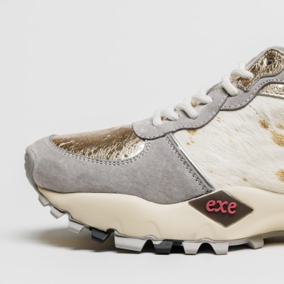 Sapatilha cinzenta com detalhes dourados e branco manchado, etiqueta 'exe' na lateral