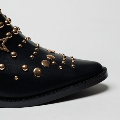 Bota preta de couro com tachas metálicas douradas e sola preta