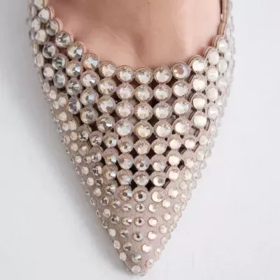 Sapato de salto alto bege com strass transparentes e bico fino em fundo branco