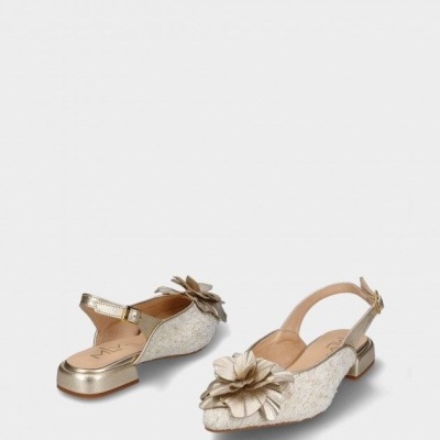 Sapatos femininos bege com salto baixo dourado e flor decorativa dourada.