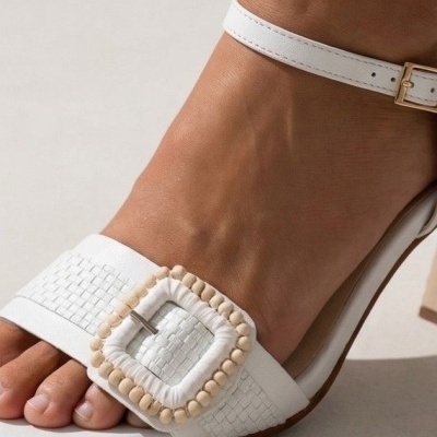 Sandália branca aberta com fivela decorativa e tira no tornozelo.