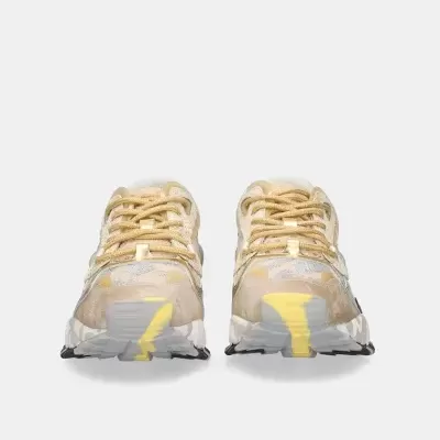 Par de ténis bege e amarelo com sola cinzenta em fundo branco