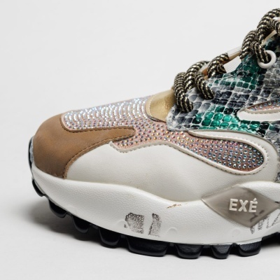 Tênis branco com detalhes em castanho e verde com pedras brilhantes e texto EXÉ na sola