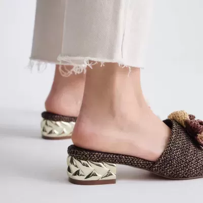 Sapatos mule castanhos com tacão dourado e calças claras com bainha desfiada