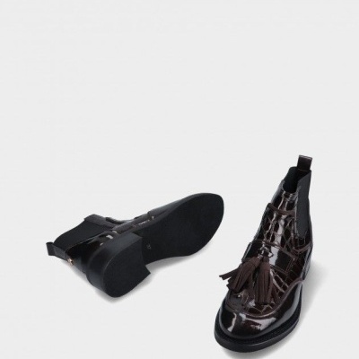 Botins castanhos de verniz com padrão crocodilo e pompons em fundo branco