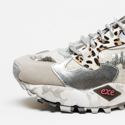 Ténis desportivo bege com detalhes metálicos, padrão animal print e sola camuflada