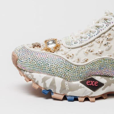 Sapatilha branca decorada com brilhos, strass e pérolas, sola camuflada com texto exe.