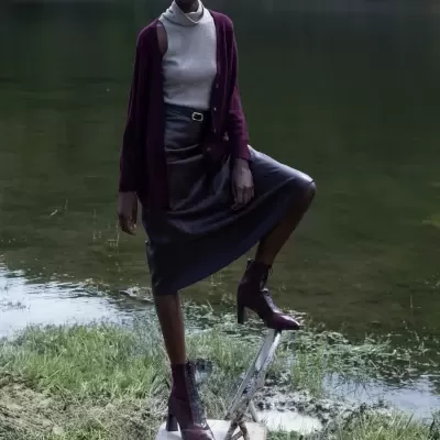 Mulher com roupa outonal em ambiente natural junto a rio.