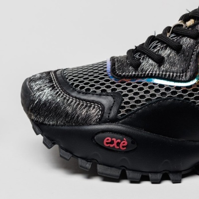 Calçado desportivo preto com sola preta e logo exé