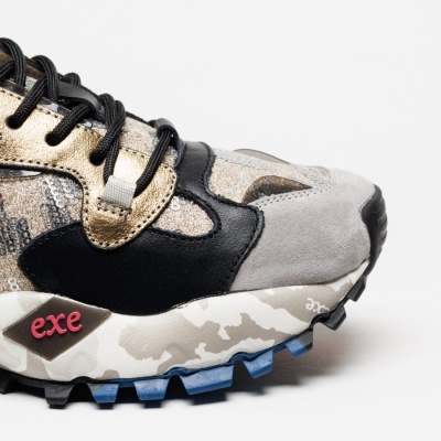 Ténis colorido com detalhes dourados, preto e cinza e sola camuflada azul e cinza.