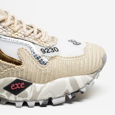 Tênis desportivo bege com texto 9230 e 99, sola camuflada e logo exe