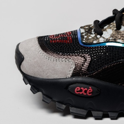 Sapatilha desportiva preta e cinza com detalhes metálicos e logo exè na sola