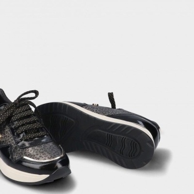 Par de sapatilhas pretas com padrão animal print e sola branca em fundo cinza