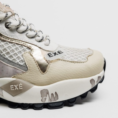 Sapatilha desportiva branca com detalhes metálicos e texto EXÉ