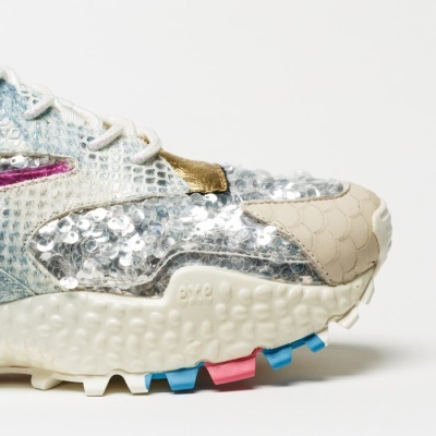 Ténis com detalhes em escamas e sequins prateados, sola branca texturizada com cores azul e rosa.