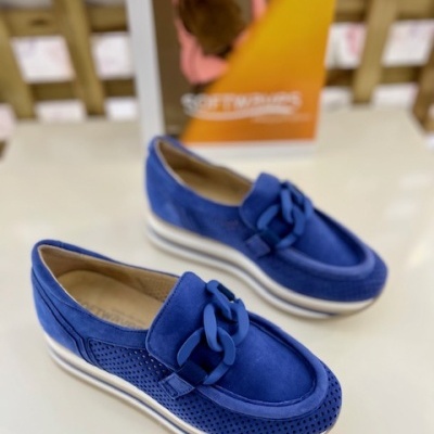 Mocassins azuis em camurça com detalhe em corrente e sola branca sobre superfície branca