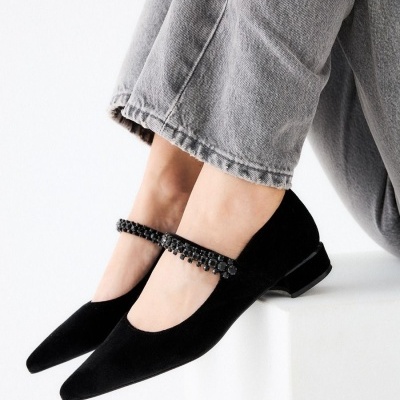 Sapatos pretos femininos de salto baixo com correia decorativa e calças cinzentas