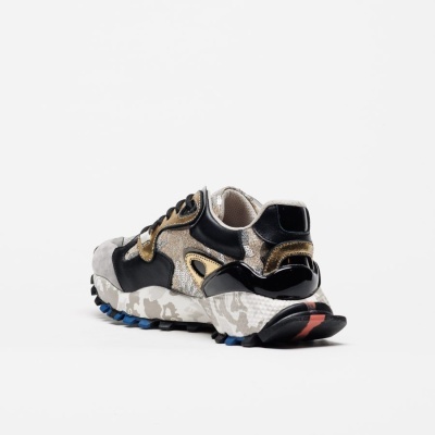 Ténis multicolorido com padrão camuflado na sola e detalhes em dourado e preto.