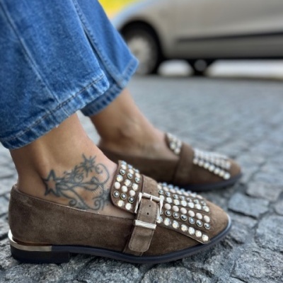 Sapatos mocassim castanhos com tachas e fivela numa calçada