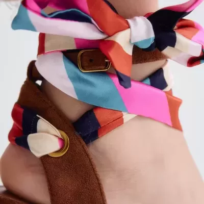 Sandália castanha com salto plataforma em ráfia colorida e tiras de tecido colorido amarradas no tornozelo.