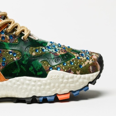Tênis desportivo em camuflado verde com pedras azuis e sola branca texturada