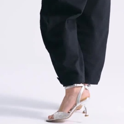 Sandálias femininas de salto prata exibidas com calças pretas.