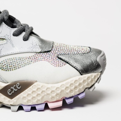 Detalhe da parte frontal de ténis branco e prata com strass e sola texturizada