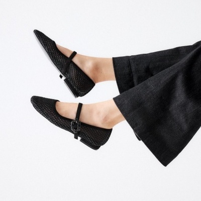 Sapatos pretos rasos com padrão entrelaçado e tira fina em fundo branco