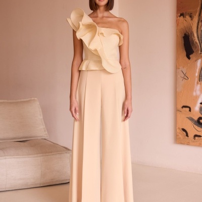 Mulher com roupa creme num ambiente interior com decoração neutra.