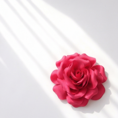 Flor artificial cor-de-rosa em fundo branco com luz solar