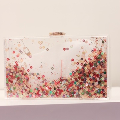 Bolsa clutch transparente com lantejoulas coloridas no interior.