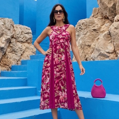 Vestido floral vermelho com acessórios em cenário azul e rochas