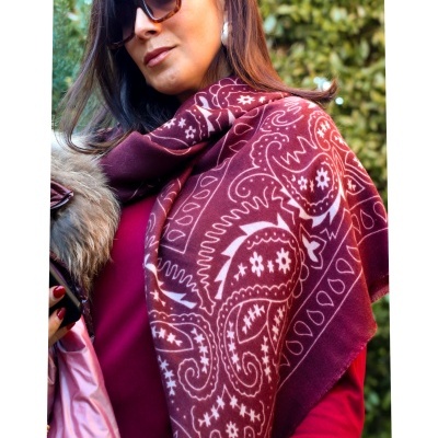 Mulher usando cachecol paisley vinho e branco com blusa vinho, óculos escuros e casaco com pelo