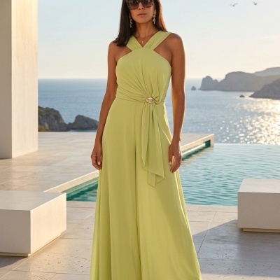 Mulher a usar vestido comprido verde com alças cruzadas junto a piscina e mar ao fundo