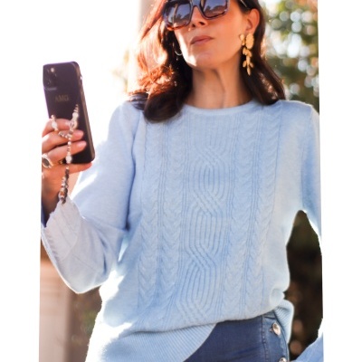 Mulher com camisola azul clara segurando telemóvel negro usando óculos de sol