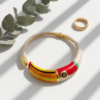 Colar rígido com padrão de tucano colorido e anel dourado em superfície branca