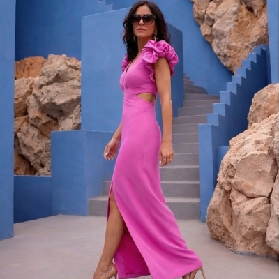 Vestido longo rosa com mangas bufantes usado por mulher com sapatos de salto nude em ambiente com escadas azuis e pedras