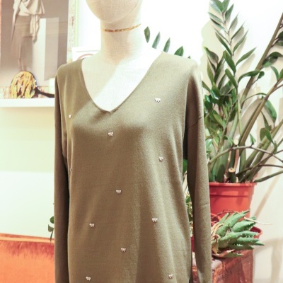 Camisola verde com pequenos laços brancos em manequim de tecido