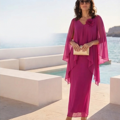 Mulher com vestido longo rosa fúcsia e clutch bege junto ao mar