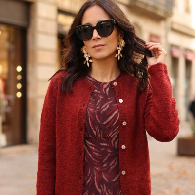 Mulher com vestido estampado vermelho e cardigan vermelho com botões numa rua urbano