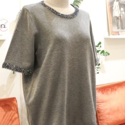 Camisola cinzenta com franjas prateadas no decote, mangas e barra